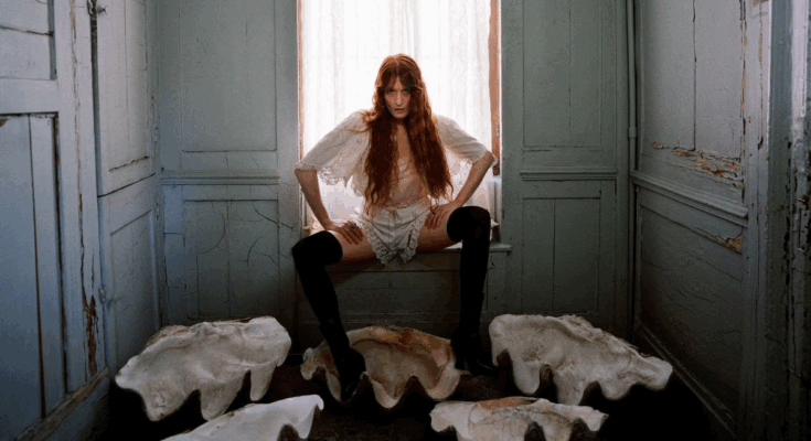 Florence Welch sitting at a window sill.
