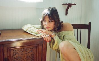 Clover County sitting on a chair and leaning on a table stand.