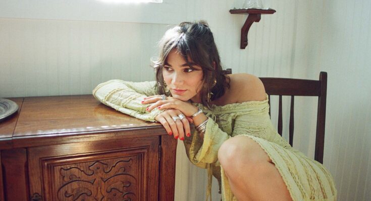 Clover County sitting on a chair and leaning on a table stand.