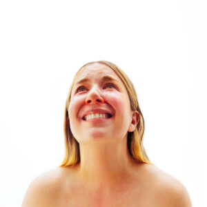 Photo of singer Austra looking up in tears with a white background