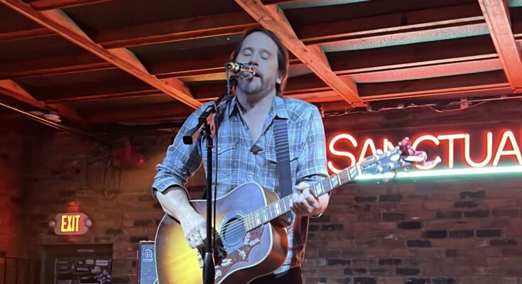 Brian Aubert playing an acoustic guitar at Sanctuary Detroit in Hamtramck, Michigan.