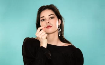 Elise Trouw wearing a black shirt in front of a blue background.