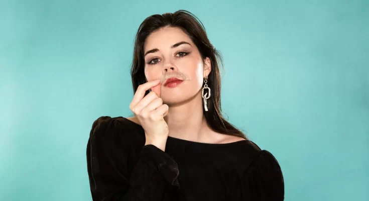 Elise Trouw wearing a black shirt in front of a blue background.